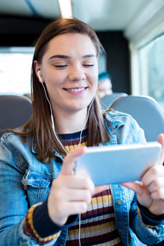 Young Woman Watching Movie On Mobile Phone During Journey To Work