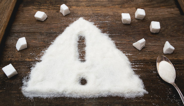 Sign of warning attention made of granulated sugar. A conceptual photo illustrating the harm from consuming white refined sugar and products containing it