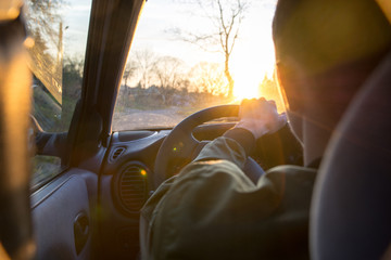 Fototapeta na wymiar young man driving a car through the town during sunset
