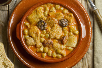 Spanish callos with chickpeas on an earthenware bowl and dish on a wooden table