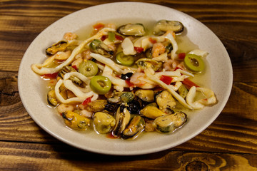Seafood salad with shrimp, squid and mussels on wooden table