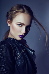 Sexy blonde Girl with tattoo in leather jacket and jeans, portrait vivid makeup and lipstick close up, facial cosmetics, professional makeup, skin care. Young sexy woman posing on dark background