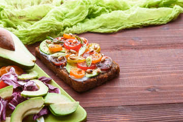 bruschetta with avocado, cherry tomatoes, blue cheese sauce, shallots. concept of a healthy breakfast with ingredients nearby