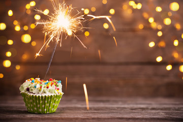 cupcake with sparkler on old wooden background