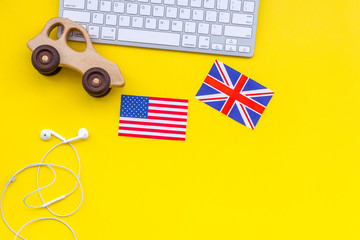 Teach english for a child. Funny english. British and american flags, computer keyboard, toy on yellow background top view copy space