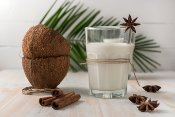 Shell of coconut and coconut milk in glass with cinnamon on wooden table.