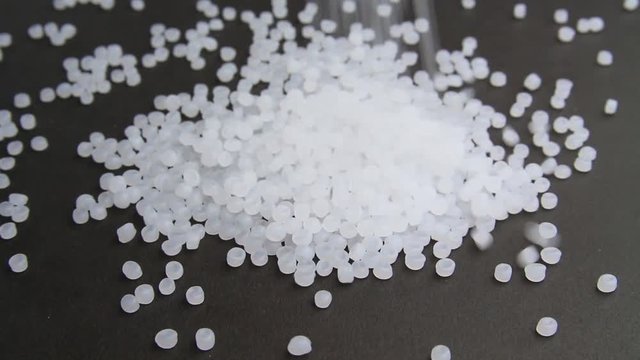 Plastic pellets crumbles to the table . Plastic raw materials in granules for industry. Polymer resin.