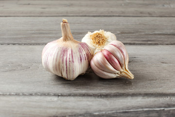 Garlic bulbs, purple cloves under cracked skin on gray wood table.