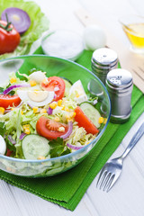 fresh spring salad of vegetables on a white wooden table.