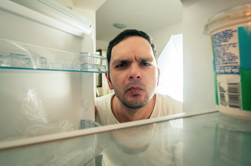 Funny man looking into the fridge