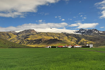Fototapeta na wymiar Iceland. Cozy cottages at the foot of graceful mountains