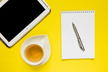 Notepad, pen, tea on a yellow background flat top view with copy space,layout,mocap