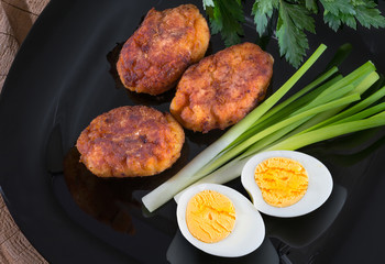 Chops, eggs and greenery, on a wooden background. Close-up.