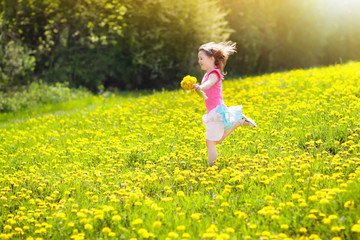 Fototapeta premium Kids play. Child in dandelion field. Summer flower