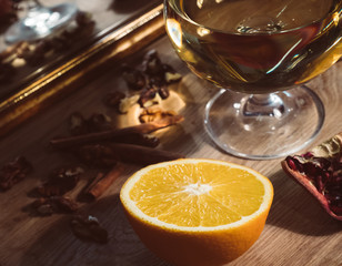 A glass of white wine as the central element of the composition surrounded by orange, nuts and pomegranate.
