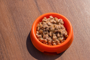 Canned food for cats or dogs in a orange plastic bowl
