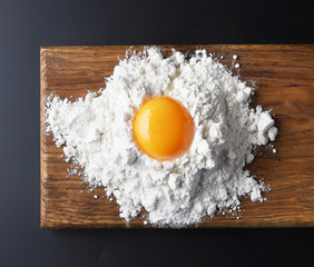 flour and egg yolk on wooden cutting board