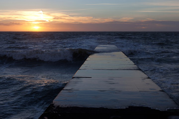 beautiful ocean sunset on the dock surrounded by waves