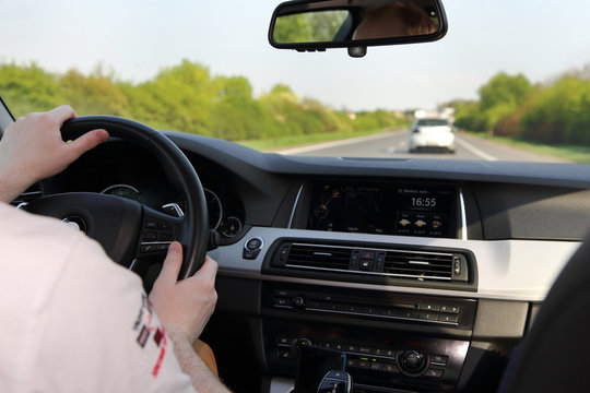 Kierowca kieruje nowoczesnym samochodem osobowym na autostradzie w słoneczny dzień.