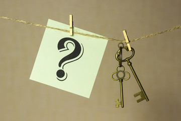 Vintage key hanging on a rope on a gold background, next sticker with question mark