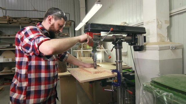 man carpenter in a shirt using drilling machine in slowmotion