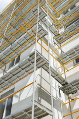 scaffolding near a new house, building exterior, construction and repair industry, white wall and window, yellow pipe