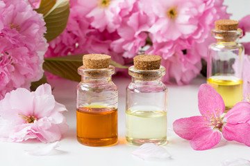 Bottles of essential oil with pink cherry blossoms