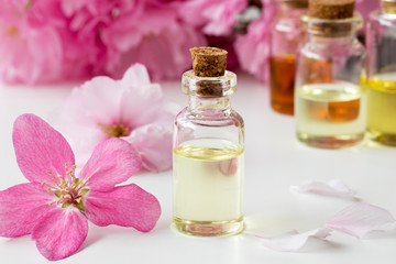 Fototapeta na wymiar A bottle of essential oil with pink cherry blossoms