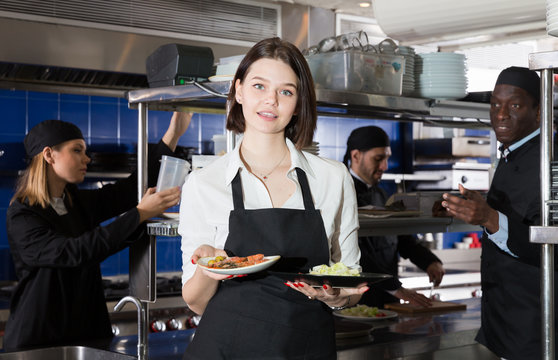 Portrait of female waiter who is standing with order on kitchen