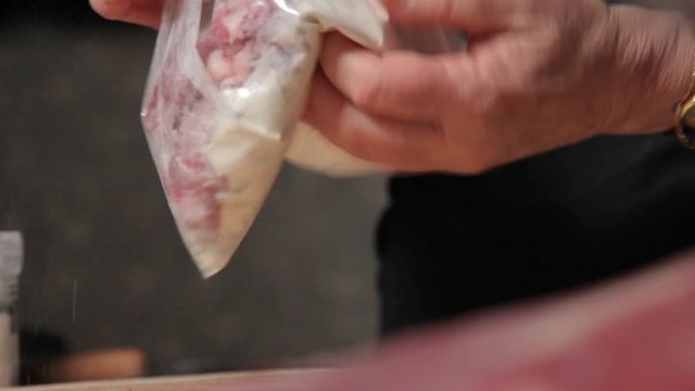 Covering portions of pork with flour.