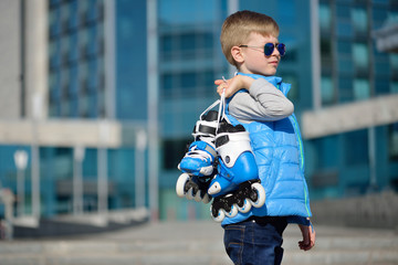 Young beautiful boy with roller skates in his hands