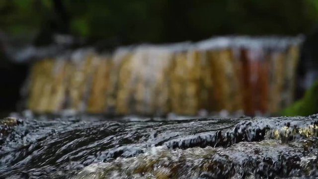 stream running through devils pulpit gorge with distant waterfall blurred in background