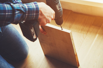 mans hands drilling wooden plank