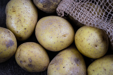 Tasty potatoes on a wooden table. Vegetables on the kitchen table in a jute sack.