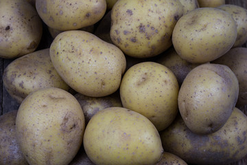 Tasty potatoes on a wooden table. Vegetables on the kitchen table in a jute sack.
