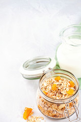 Jar with homemade granola or oatmeal muesli with nuts and dried fruits and milk. Healty diet breakfast, vegeterian food concept