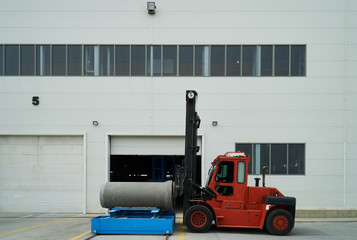 Fototapeta na wymiar Heavy Forklift loader for warehouse works outdoors with concrete pipes. Industrial production of cement products. Industry manufacturing concept