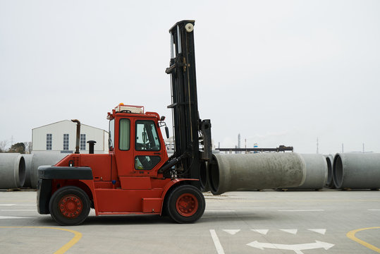 Heavy Forklift loader for warehouse works outdoors with concrete pipes. Industrial production of cement products. Industry manufacturing concept