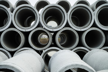 Stacked cement pipes at concrete factory, outdoors warehouse . Industrial production of cement products. Industry manufacturing concept