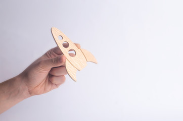 Wooden rocket in hand on a white background. A man is playing with a rocket. Minimalism, space...