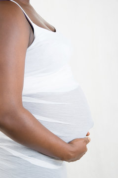 pregnant woman holding her belly on a light background