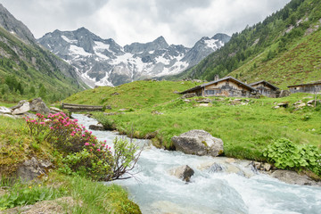 Fototapeta na wymiar Almhütten am Wildbach mit Gletscher im Hintergrund