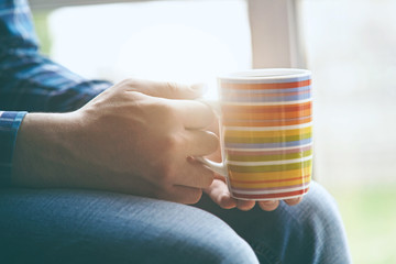 man sitting near window with cup of morning coffee or tea