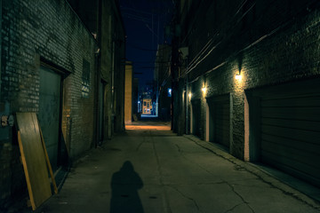 Shadow of a person in a dark city alley at night