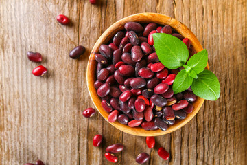 Red raw beans with greens on a wooden table.