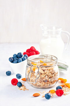 Jar with homemade granola or oatmeal muesli with nuts, dried fruits and fresh berries. Healty diet breakfast, vegan or vegeterian food concept