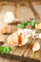 Heads of garlic with parsley on a wooden table.
