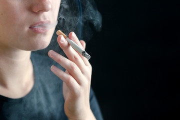 Girl Smoking a cigarette. On black background copy space