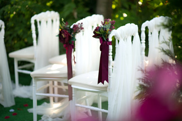 White vintage style chairs decorated with red / claret flowers