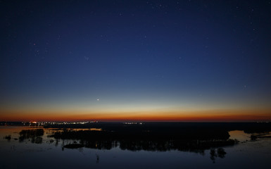 Night sky with stars above the river during the spring flood. View of the starry space.